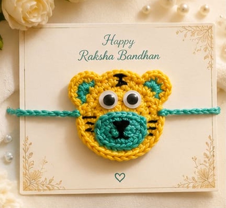 Handmade crochet tiger face rakhi in yellow and teal with googly eyes